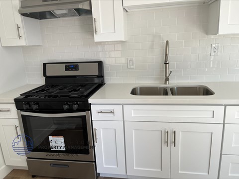 a white kitchen with a stove and a sink